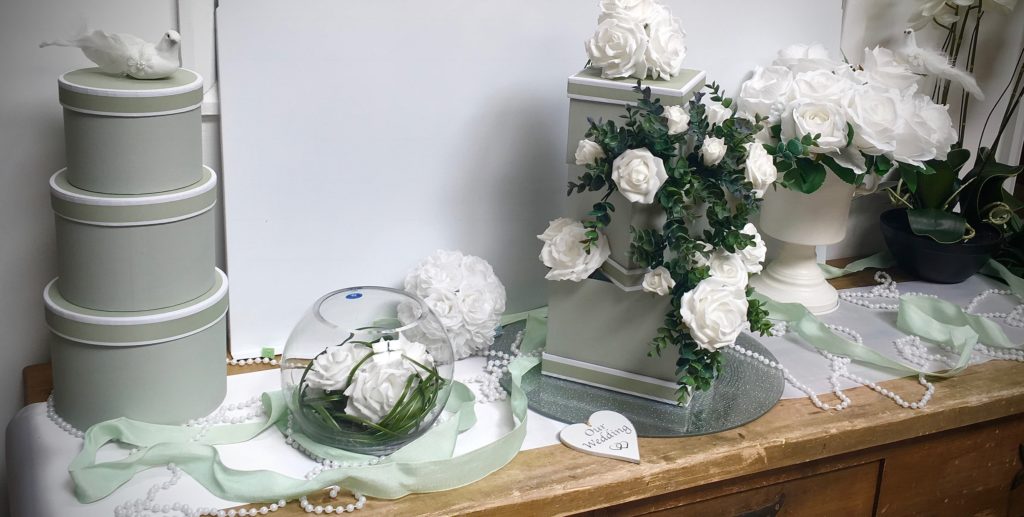 This charming display of light grey flower hat boxes and gift boxes are shown with dove, white roses, beads and mint colour ribbon.