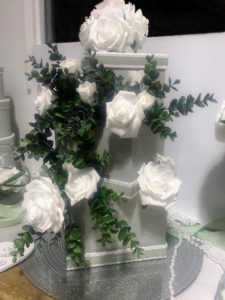 white roses with eucalyptus stems on a glittered mirror plate